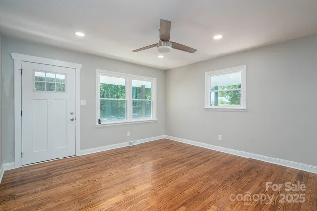 a view of an empty room with wooden floor and a window