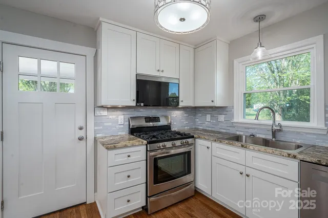 a kitchen with white cabinets stainless steel appliances and a window