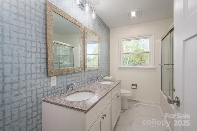 a bathroom with a granite countertop sink a toilet and a mirror