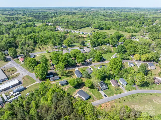 an aerial view of residential houses with outdoor space and trees