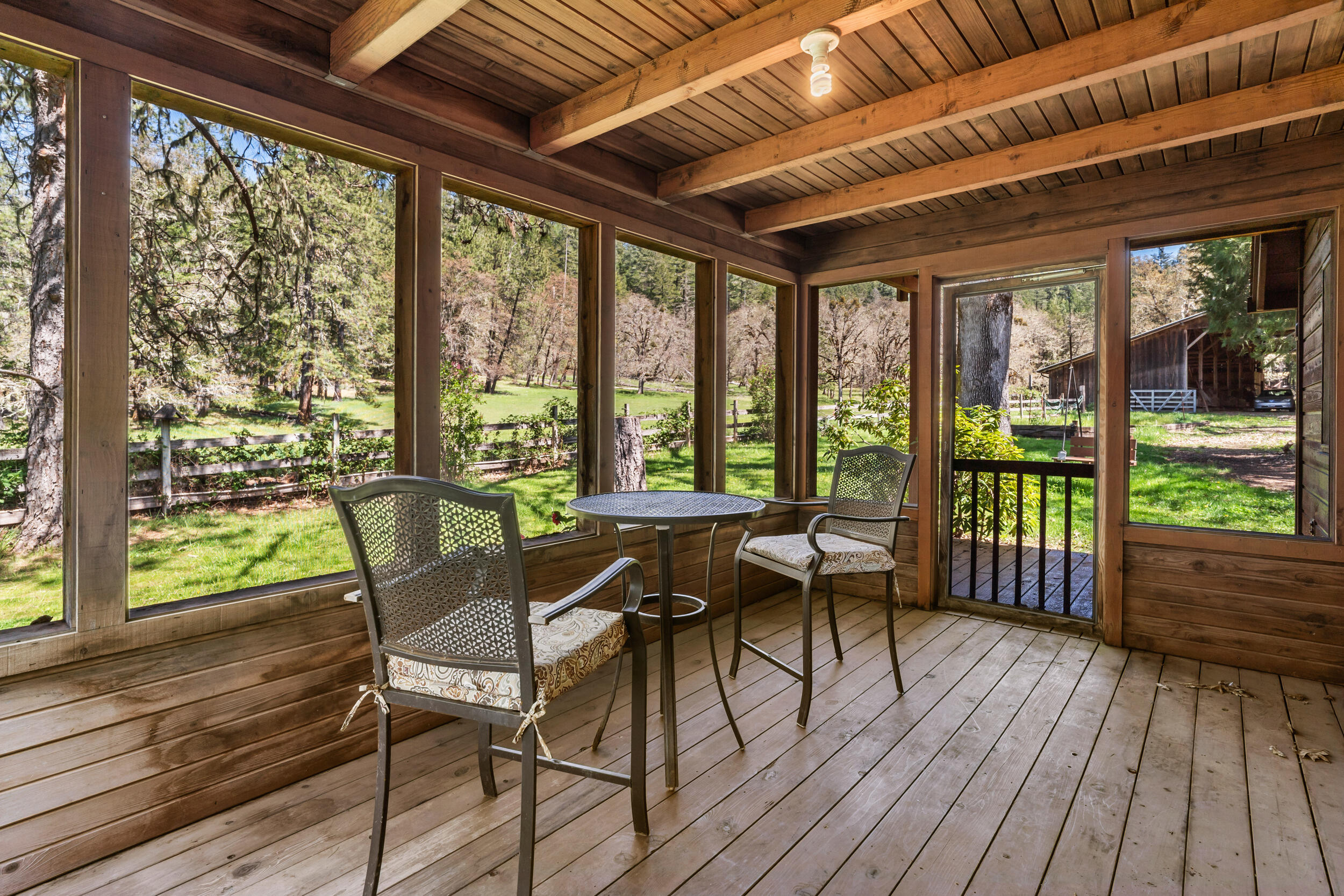 7589 Takilma Road Cave Junction, OR 97523 - Photo 25 of 54 a dining room with wooden floor glass table and chairs