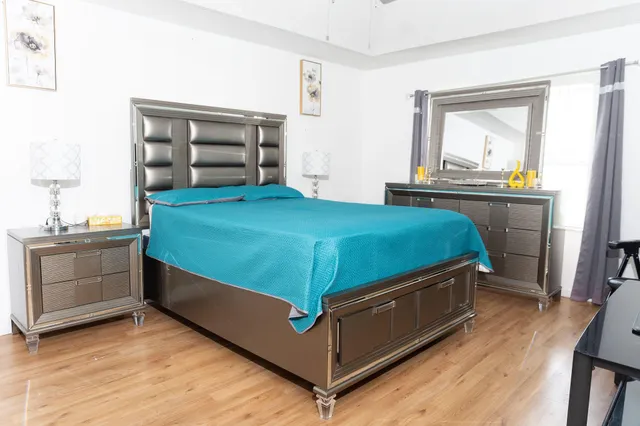 a bed sitting in a bedroom next to a cabinet with wooden floor
