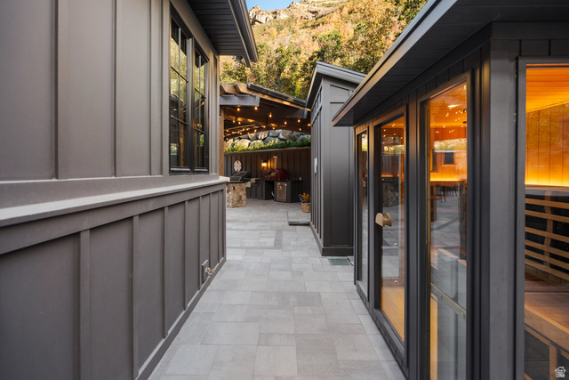 1141 South Oak Leaf Lane Springville, UT 84663 - Photo 117 of 147 Exterior courtyard featuring paver flooring, modern board and batten siding, multiple buildings with dark-framed windows, and an outdoor kitchen area with string lighting