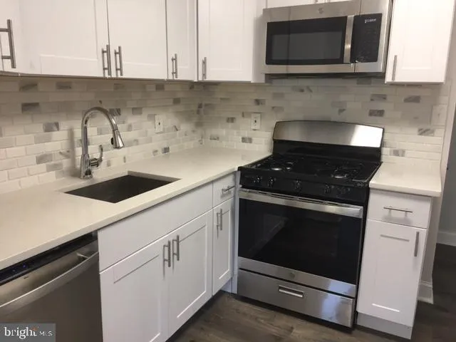a kitchen with granite countertop white cabinets stainless steel appliances and a sink