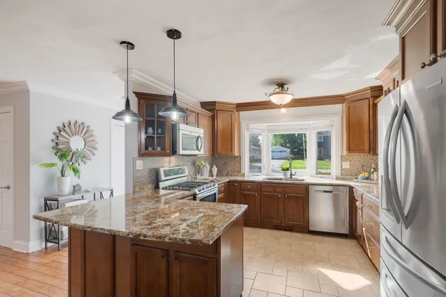 a kitchen with stainless steel appliances granite countertop a sink a stove and a refrigerator
