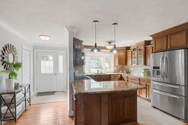 a kitchen with stainless steel appliances granite countertop a refrigerator a sink a stove and a wooden floors