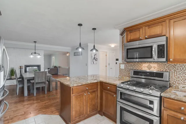 a kitchen with stainless steel appliances granite countertop a stove top oven a sink a dining table and chairs