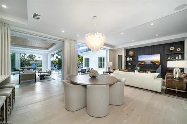 a dining hall with couches a flat tv screen and a dining table with garden view