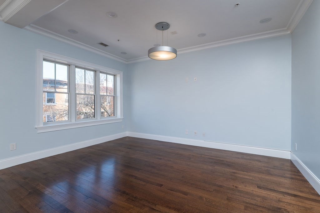 142 Fuller Street, Unit 4 Brookline, MA 02446 - Photo 36 of 40 an empty room with wooden floor and windows