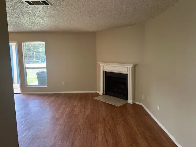 an empty room with wooden floor a fireplace and windows
