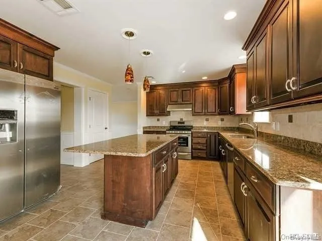 a kitchen with stainless steel appliances granite countertop a stove a sink and a refrigerator