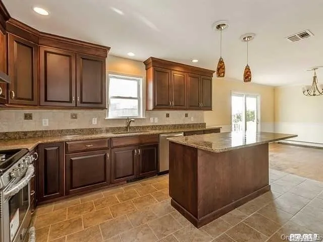 a kitchen with stainless steel appliances granite countertop a stove a sink and a microwave