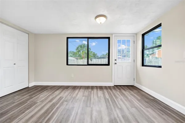 an empty room with wooden floor and windows