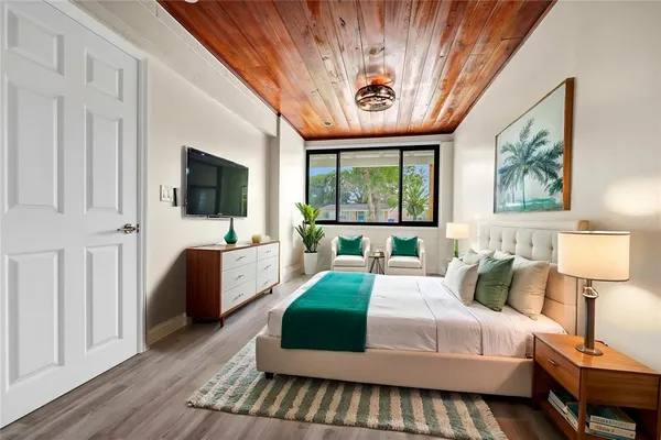 a bedroom with a large bed a flat tv screen and a dresser