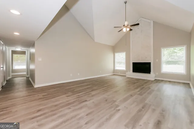 an empty room with wooden floor fireplace and windows