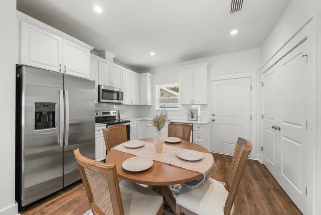 a kitchen with stainless steel appliances granite countertop a dining table chairs refrigerator and a sink