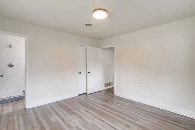an empty room with wooden floor and windows