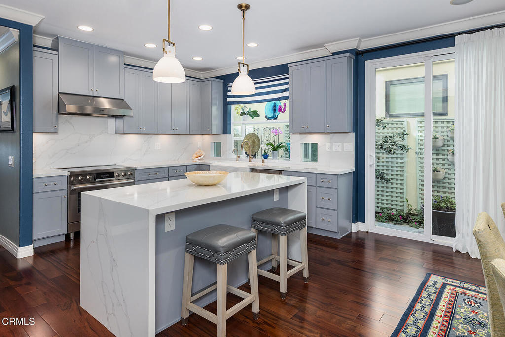 411 22nd Street Huntington Beach, CA 92648 - Photo 16 of 38 a kitchen with stainless steel appliances granite countertop a stove a refrigerator a sink dishwasher a dining table and chairs with wooden floor