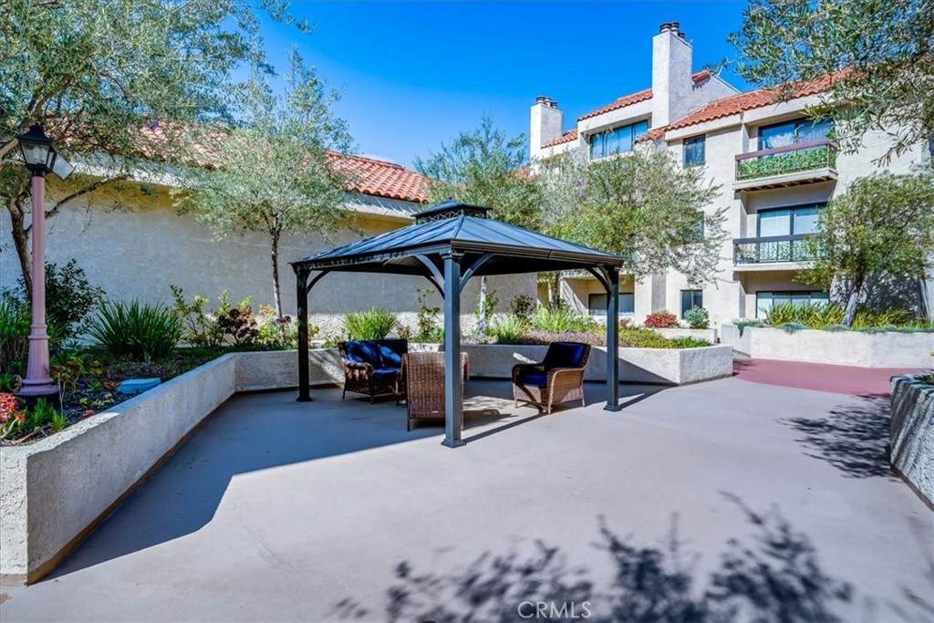 8180 Manitoba Street, Unit 302 Playa del Rey, CA 90293 - Photo 22 of 31 a view of a patio with a table and chairs under an umbrella with potted plants