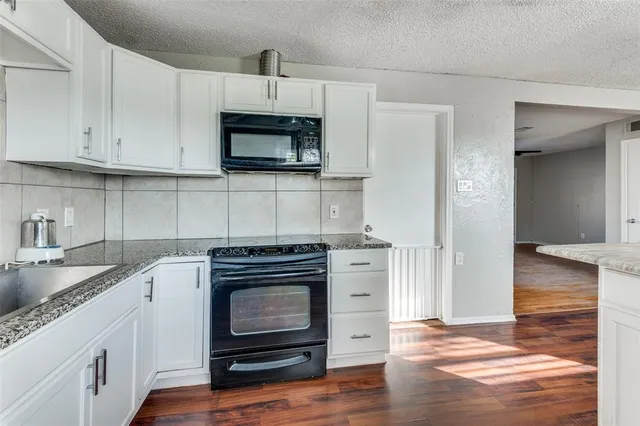 a kitchen with white cabinets and appliances