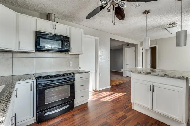 a kitchen with stainless steel appliances kitchen island granite countertop a stove and a microwave