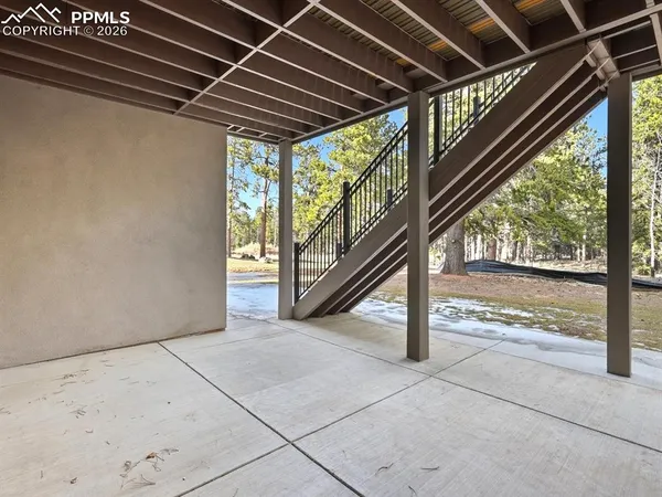 a view of an empty room with wooden floor and stairs