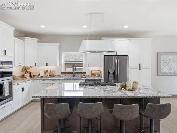 a kitchen with stainless steel appliances granite countertop a kitchen island a stove a table and chairs in it