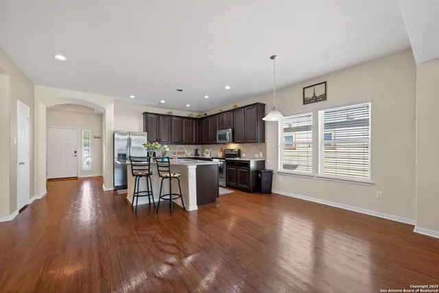 a open kitchen with stainless steel appliances wooden floor and a refrigerator