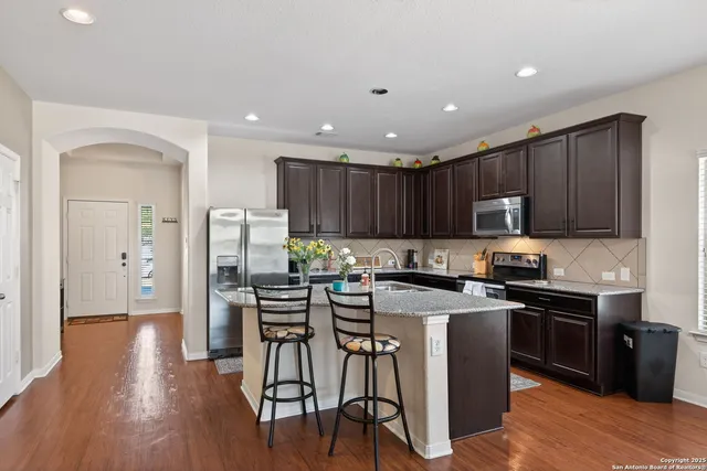 a kitchen with stainless steel appliances granite countertop wooden cabinets a stove top oven a sink and dishwasher