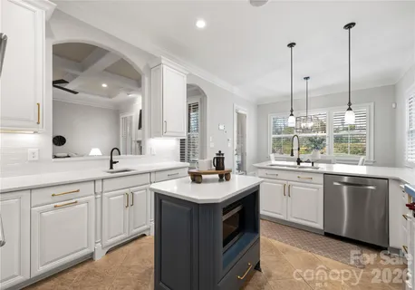 a kitchen with stainless steel appliances granite countertop a stove top oven a sink dishwasher and a microwave oven with white cabinets