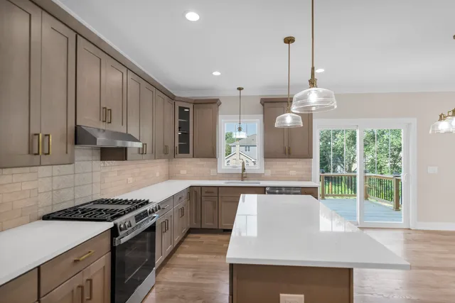 a large kitchen with stainless steel appliances granite countertop a stove a sink and a white cabinets