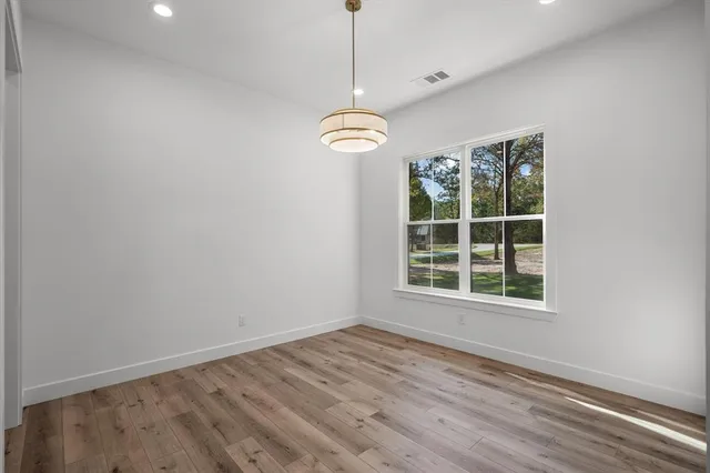 a view of a hallway with wooden floor and cabinet