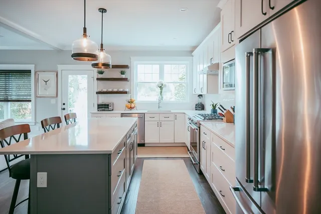 a kitchen with kitchen island granite countertop a sink appliances cabinets and a window