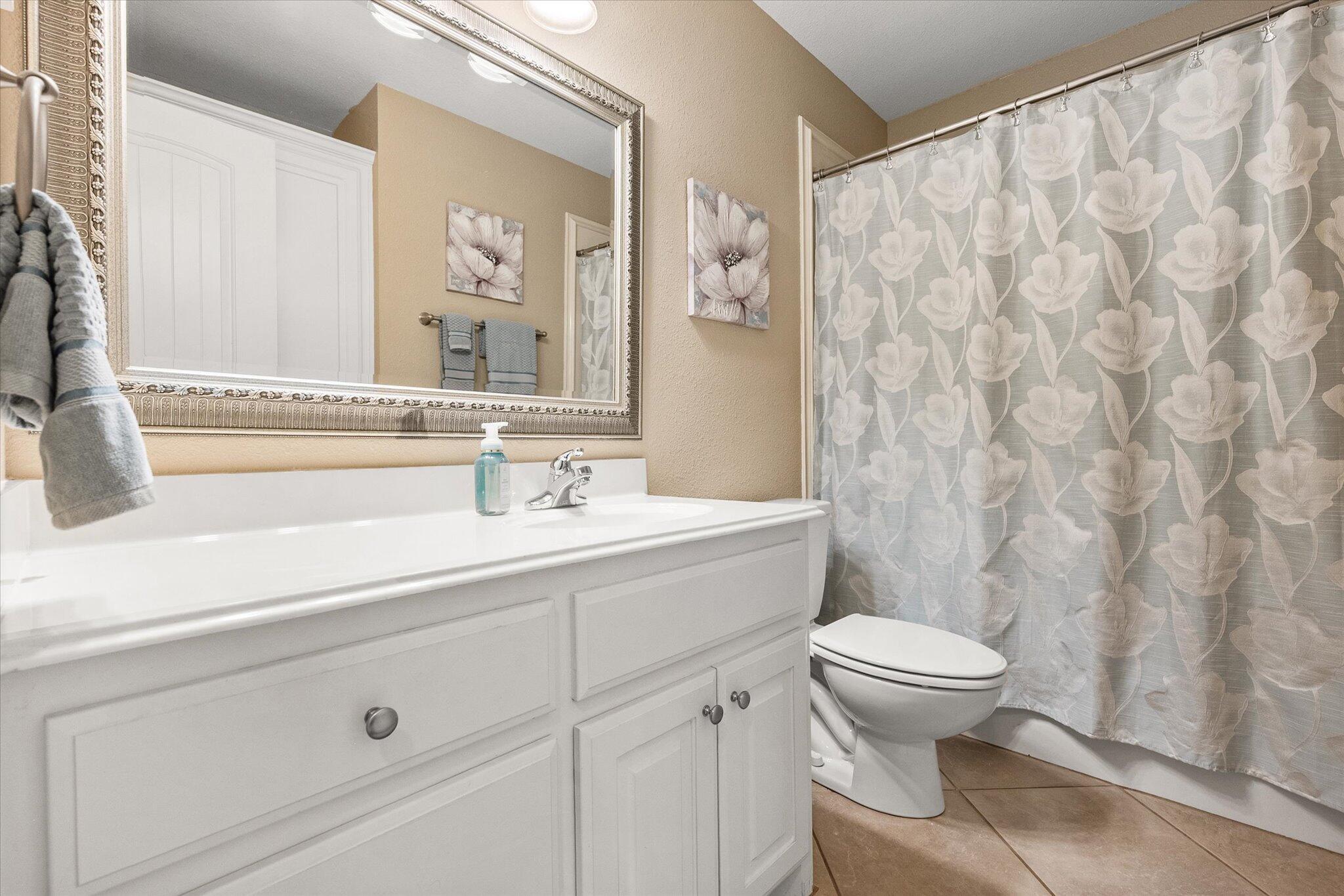 5908 110th Street Lubbock, TX 79424 - Photo 18 of 31 a bathroom with a sink a toilet and a mirror