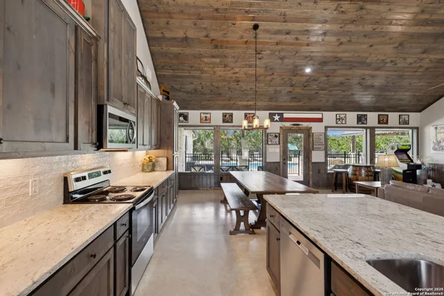 a kitchen with stainless steel appliances granite countertop a sink a stove and a wooden cabinets