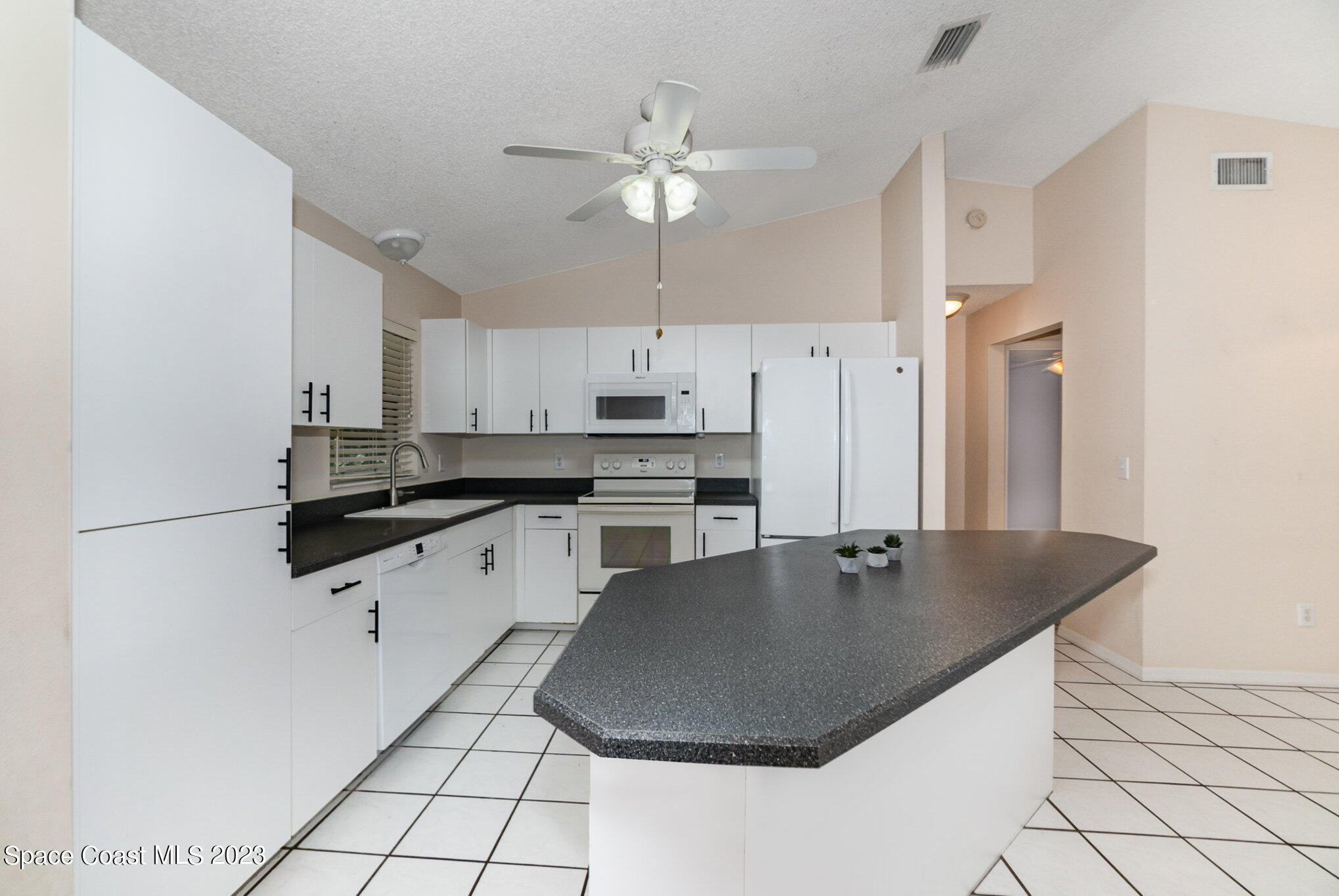 2399 Angel Road Palm Bay, FL 32909 - Photo 9 of 26 a kitchen with stainless steel appliances granite countertop a sink a stove a refrigerator and white cabinets