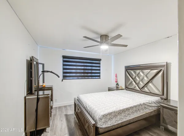 a bedroom with a bed and a dresser with wooden floor