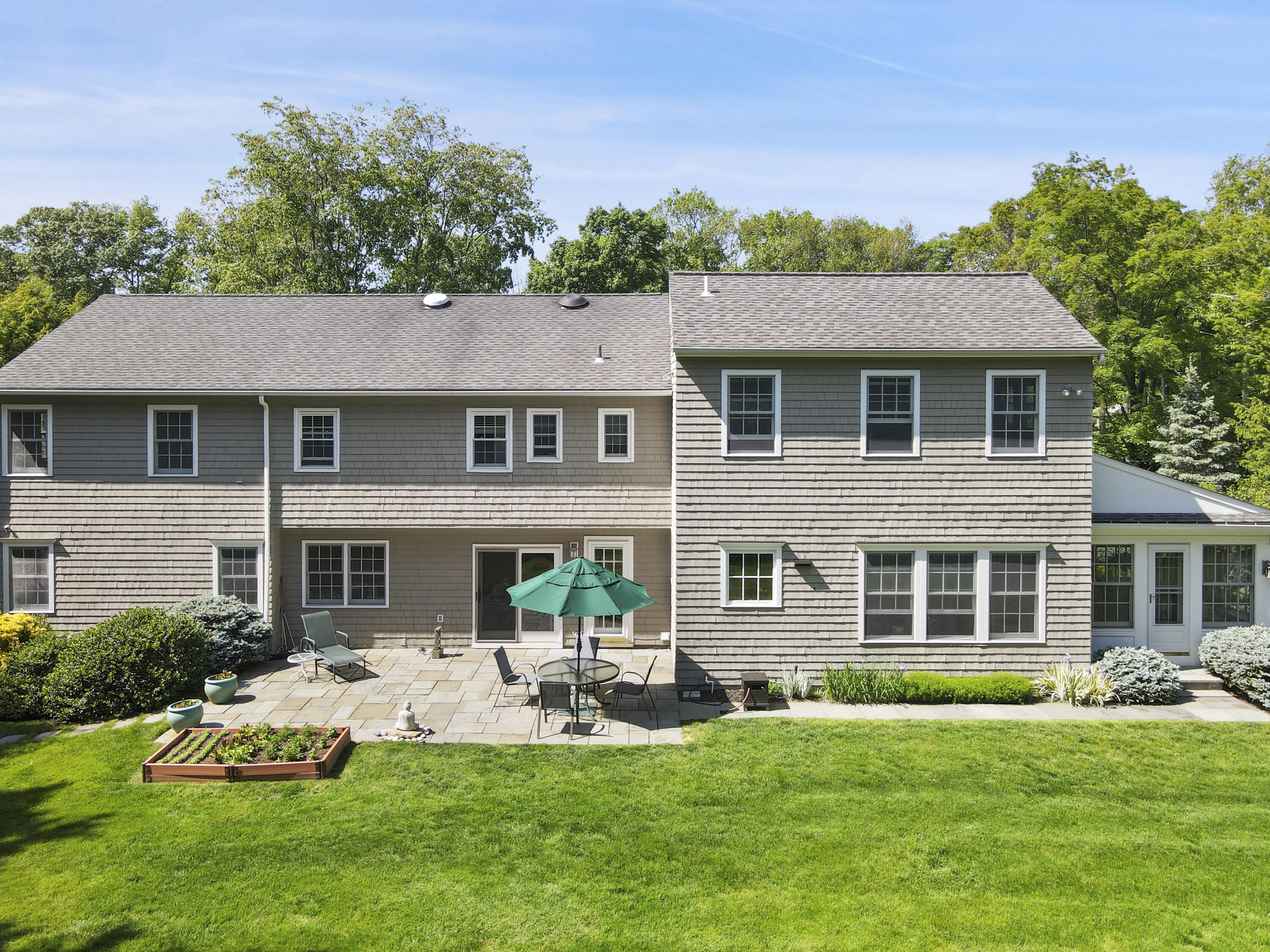 34 Summit Ridge Road New Canaan, CT 06840 - Photo 18 of 28 a front view of a house with a yard table and chairs