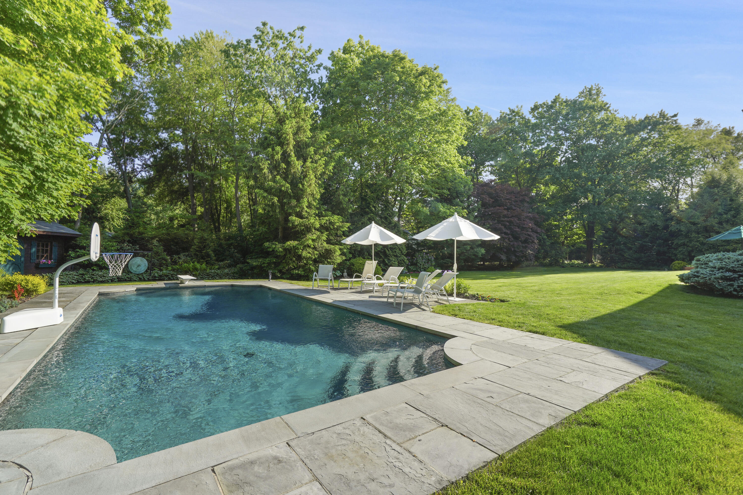 34 Summit Ridge Road New Canaan, CT 06840 - Photo 22 of 28 a view of a swimming pool with a table and chairs under an umbrella