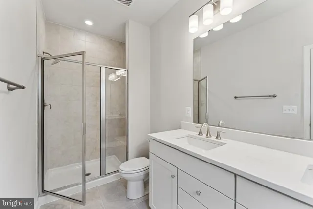 a bathroom with a shower sink vanity mirror and toilet