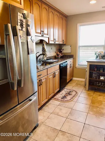 a kitchen with stainless steel appliances granite countertop a refrigerator a stove a sink and a window