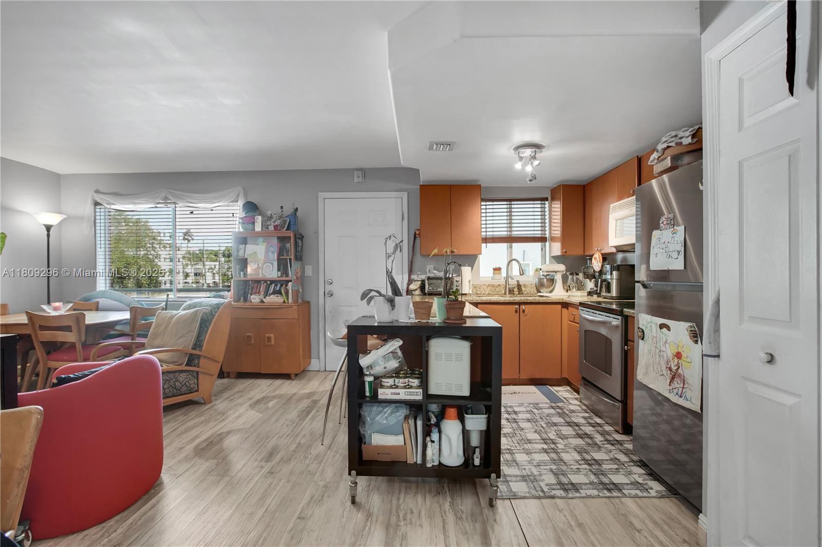3101 Southwest 27th Avenue, Unit 203 Miami, FL 33133 - Photo 11 of 25 a kitchen with stainless steel appliances granite countertop wooden floor a refrigerator a sink dishwasher a dining table and chairs with wooden floor