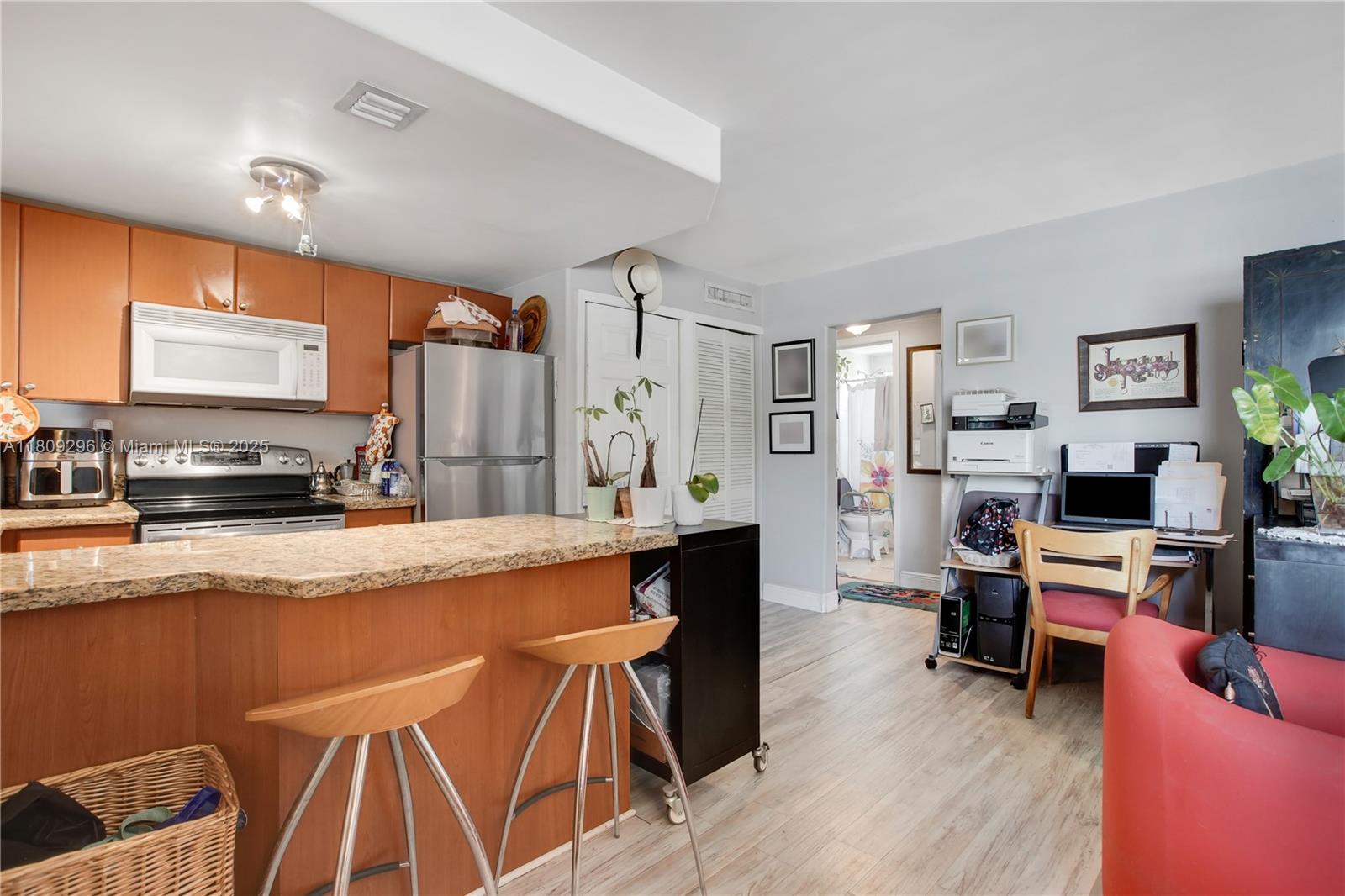 3101 Southwest 27th Avenue, Unit 203 Miami, FL 33133 - Photo 10 of 25 a large kitchen with stainless steel appliances a stove a refrigerator a dining table and chairs with wooden floor