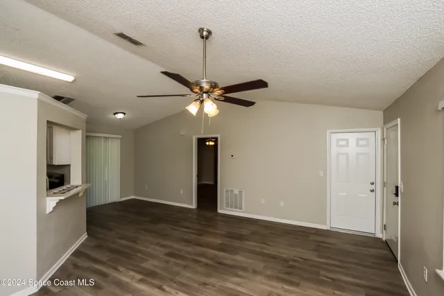 a view of an empty room with window and wooden floor