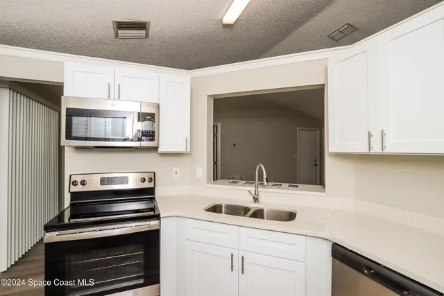 a kitchen with white cabinets and appliances