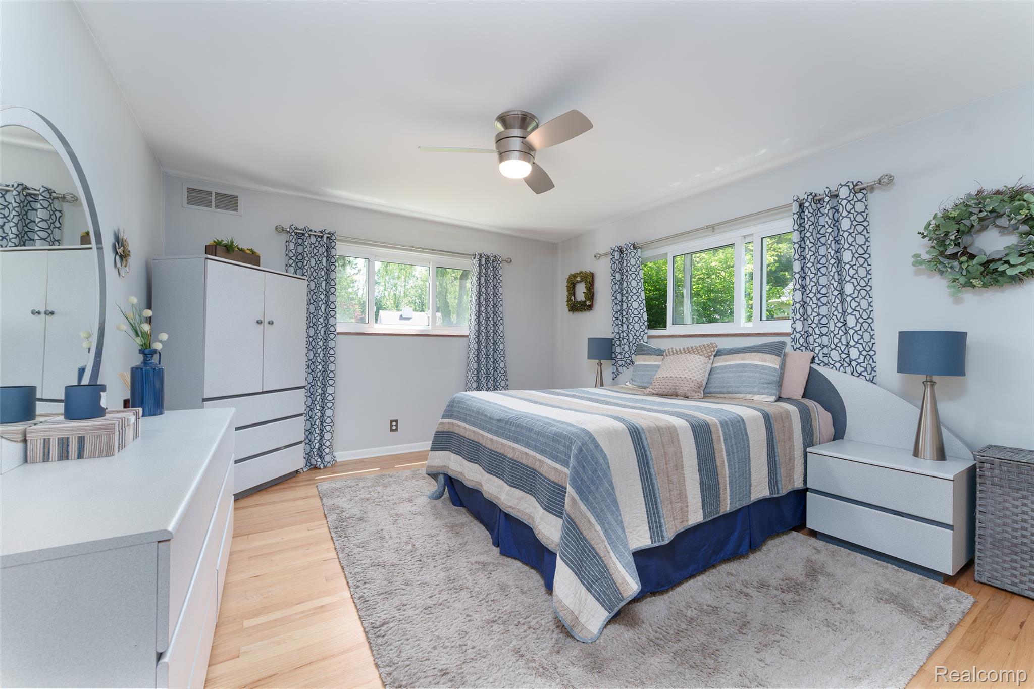 2172 Devonshire Road Bloomfield Hills, MI 48302 - Photo 24 of 45 Bright room featuring multiple windows, a ceiling fan with integrated lighting, light wood flooring, and a neutral wall color