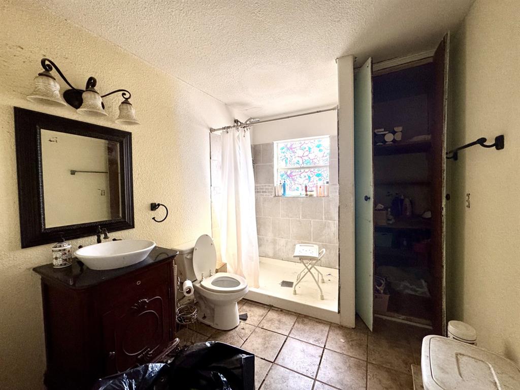 613 West Main Street Crowley, TX 76036 - Photo 19 of 30 Bathroom with a textured wall, a stall shower, vanity, a textured ceiling, and light tile patterned flooring