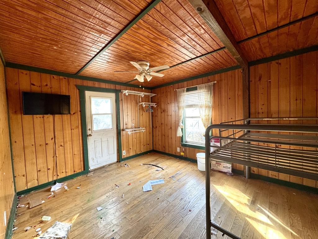 613 West Main Street Crowley, TX 76036 - Photo 20 of 30 BACK bedroom featuring wooden walls, hardwood / wood-style flooring, multiple windows, wood ceiling, and a ceiling fan - DOOR Opens to Backyard.