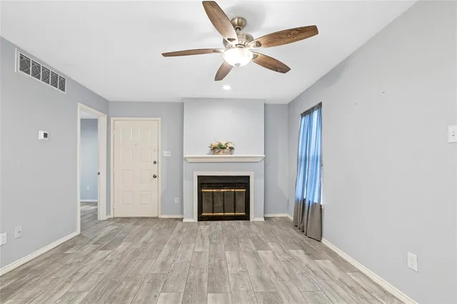 a livingroom with a ceiling fan a flat screen tv and a fireplace