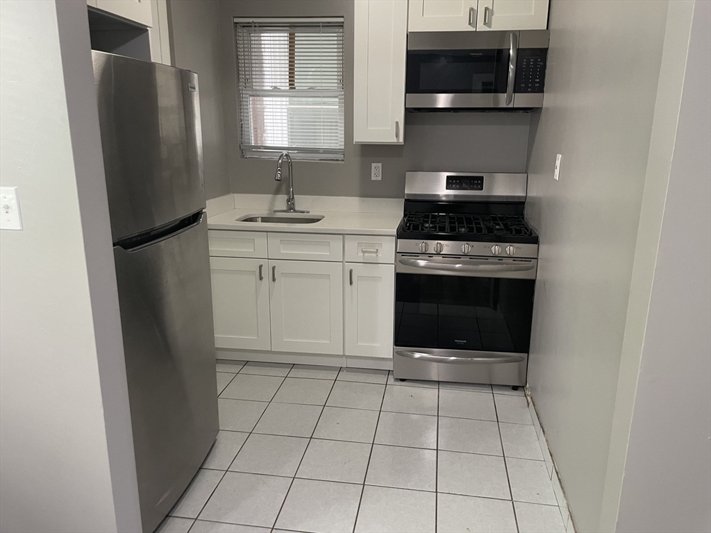 8 Cheever Court, Unit 1 Boston, MA 02128 - Photo 7 of 16 a kitchen with a stove top oven and cabinets